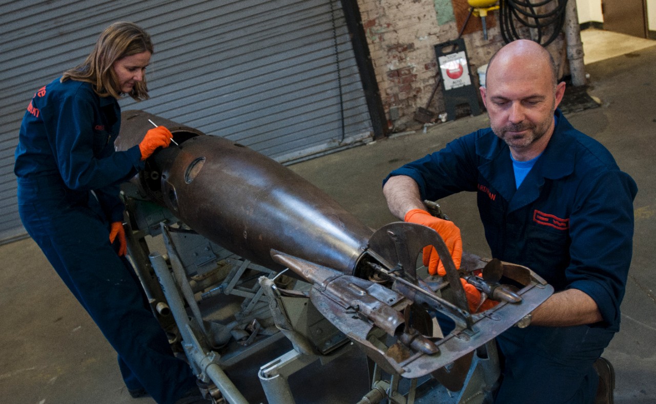 Conservators, Claudia Chemello and Paul Mardikian, perform final adjustments on the conserved torpedo to make it ready for exhibit.