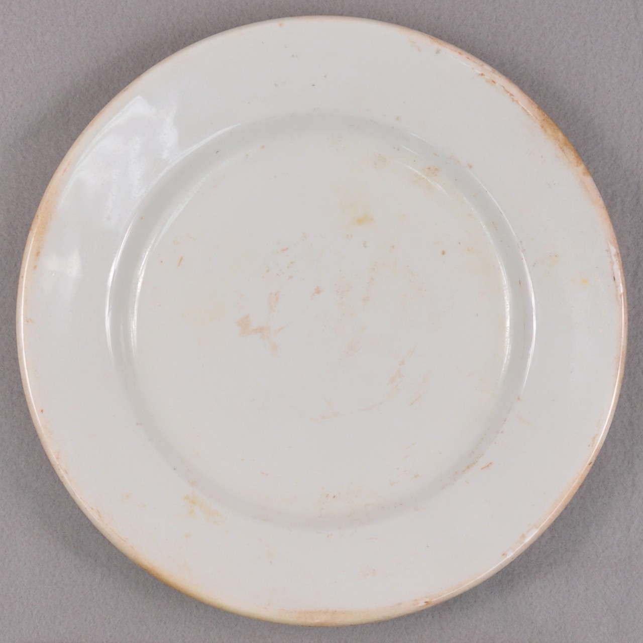 <p>An undecorated white glazed stoneware plate recovered from USS San Diego.</p>
