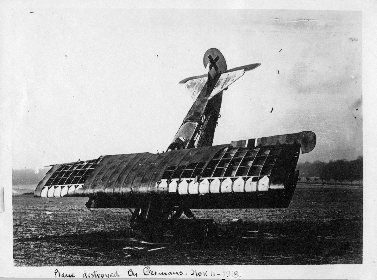 Black and white photo of a World War I plane that crashed nose first on an open field.