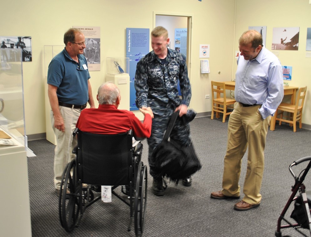 NMAS visitor in wheelchair shaking hands with sailor.