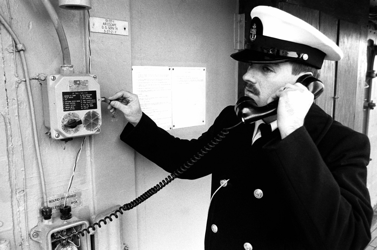 330-CFD-DN-SN-91-04377  A Chief Petty Officer uses a sound-powered phone to communicate with crew members aboard the ocean minesweeper USS Exploit (MSO-440) as the vessel travels to Naval Amphibious Base, Norfolk, Virginia, January 1, 1991. Photographed by Ron Fontaine.    Official U.S. Navy photograph, now in the collections of the National Archives.