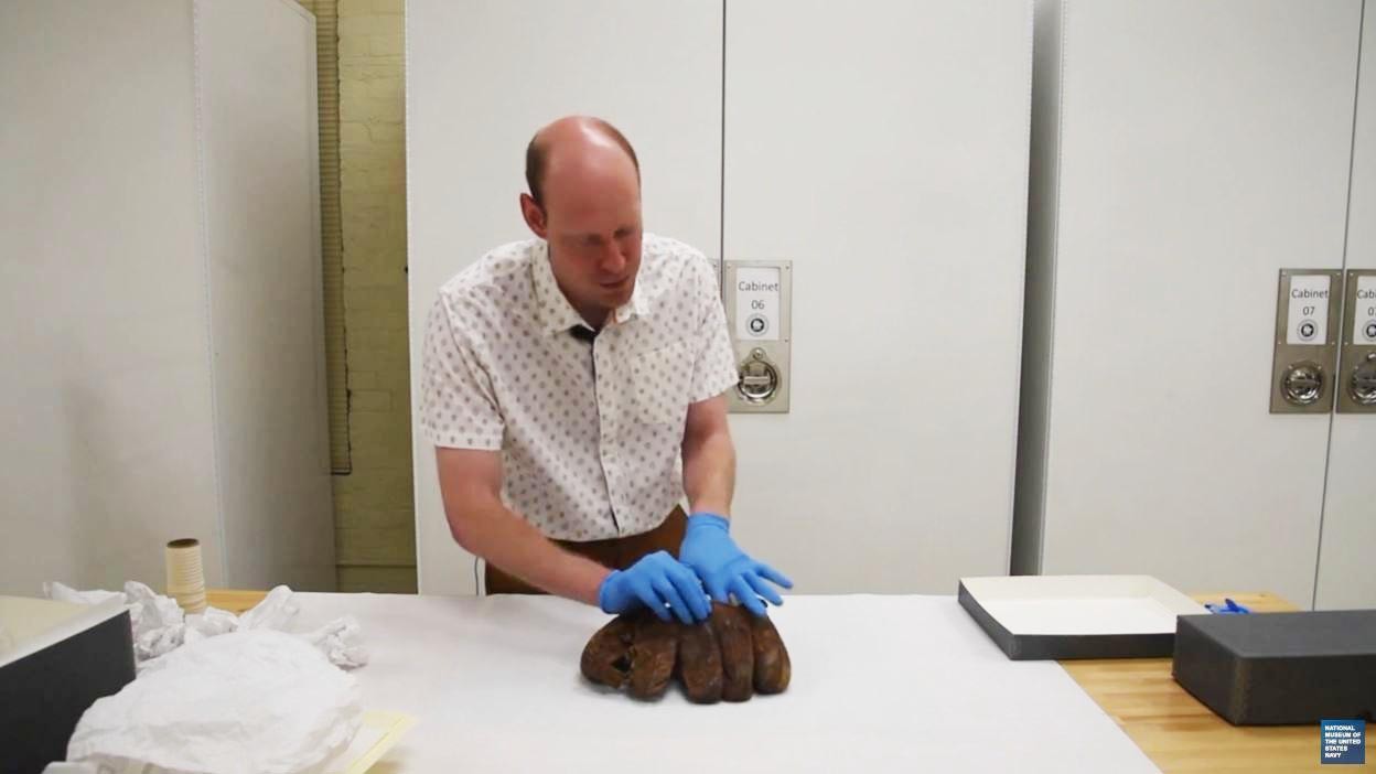 Collections Manager Wesley Schwenk attending to a baseball glove.  