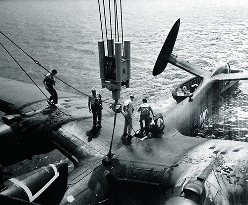 80-G-444317: PBM-5s of VP-34 during operations of USS Currituck (AV-7). PBM-5 being hoisted, May 7, 1952. National Archives Photograph.