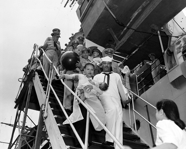 80-G-647026:   A Vietnamese mother and baby are helped down the gangway of USS Estes (AGC-12) as refugees arrive at Saigon after being evacuated from the North.  Official U.S. Navy Photograph, now in the collections of the National Archives.