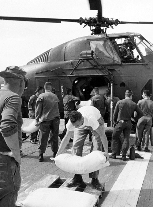 NH 93797:  USS Princeton (LPH-5), U.S. Marines loading relief supplies on a USMC/Sikorsky Ch-34 helicopter for delivery to South Vietnam.   NHHC Photograph Collection.  
