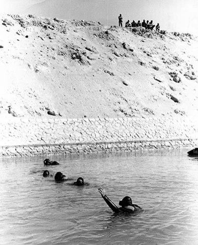 French Divers  conducting shallow water search of canal.   Watching from the embankment are Egyptian Soldiers.  Photographed by LCDR C.C. Bottinni, French Navy.   NHHC Photograph Collection, Navy Subject Files.