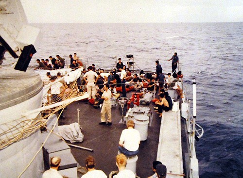428-GX-K130895:   South China Sea.  Vietnamese refugees rest on the fantail of guided missile destroyer USS Towers (DDG-9) just after being rescued from their small boat.   Photographed by PH3 Kenneth Flemings, received May 3, 1981.      Official U.S. Navy Photograph, now in the collections of the National Archives.   