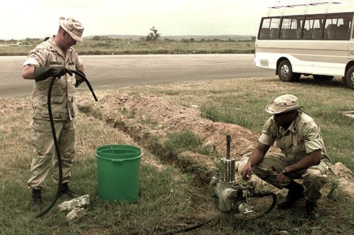 330-CFD-DM-SD-02-05512:  Operation Nobel Response.  U.S. Navy Chief Campbell, Preventative Medicine Technician (PMT) and Hospital Corpsman First Class McGhee, Independent Duty Corpsman (IDC) draw water from a local well to treat and add to the hand washing station for Marines and Sailors to use during the operation.  Photographed March 13, 1998 by SGT R.A. Ward, USMC.  Official U.S. Marine Corps photograph, now in the collection of the National Archives.  