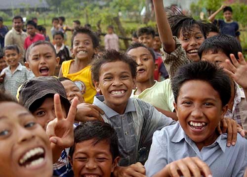 050105-N-5376G-019:   Island of Sumatra, Indonesia.  Indonesian children smile and cheer as U.S. Navy helicopters from USS Abraham Lincoln (CVN-72) fly-in purified water and relief supplies to a small village on the island of Sumatra, Indonesia.   Photographed by Photographer’s Mate 3rd Class Benjamin D. Glass.   Official U.S. Navy photograph. 