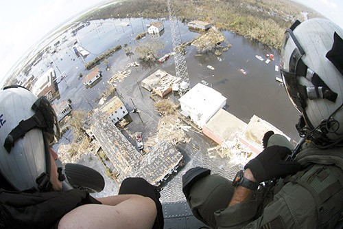 330-CFD-DN-SD-06-03455: Hurricane Katrina, 2005.  Two U.S. Navy  Search and Rescue (SAR) Swimmers, Helicopter Sea Combat Squadron 28 (HSC-28), watch a rescue unfold, while seated on the deck of their USN Sikorsky MH-60S Seahawk Helicopter, to see if their assistance is needed, September 2005.  Official U.S. Navy Photograph, now in the collections of the National Archives.   
