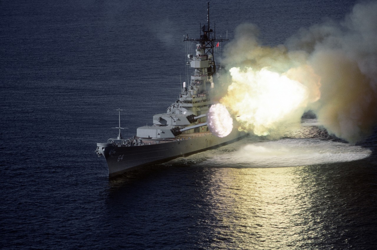 330-CFD-DN-ST-89-01388:  A port bow view of the battleship USS Wisconsin (BB 64) firing its Mark 7 16-inch/50-caliber guns to port during a fire power demonstration in the Gulf of Mexico, 8/30/1988.   PH2 Hicks, USN.  (OPA-NARA II-2016/01/10).