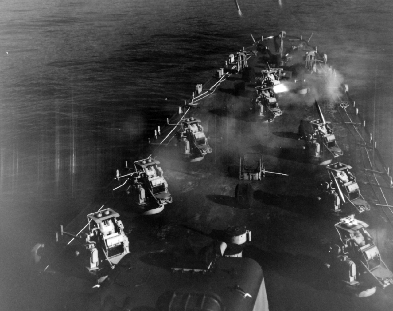 80-G-689755:  USS Carronade (IFS-1), 1955-59.  Firing rockets from deck.   Carronade was an Inshore Fire Support Ship, built to provide gunfire support to amphibious landings or operations close to shore. Official U.S. Navy Photograph, now in the collections of the National Archives.  (2017/11/01).  Photograph is extremely curved.  