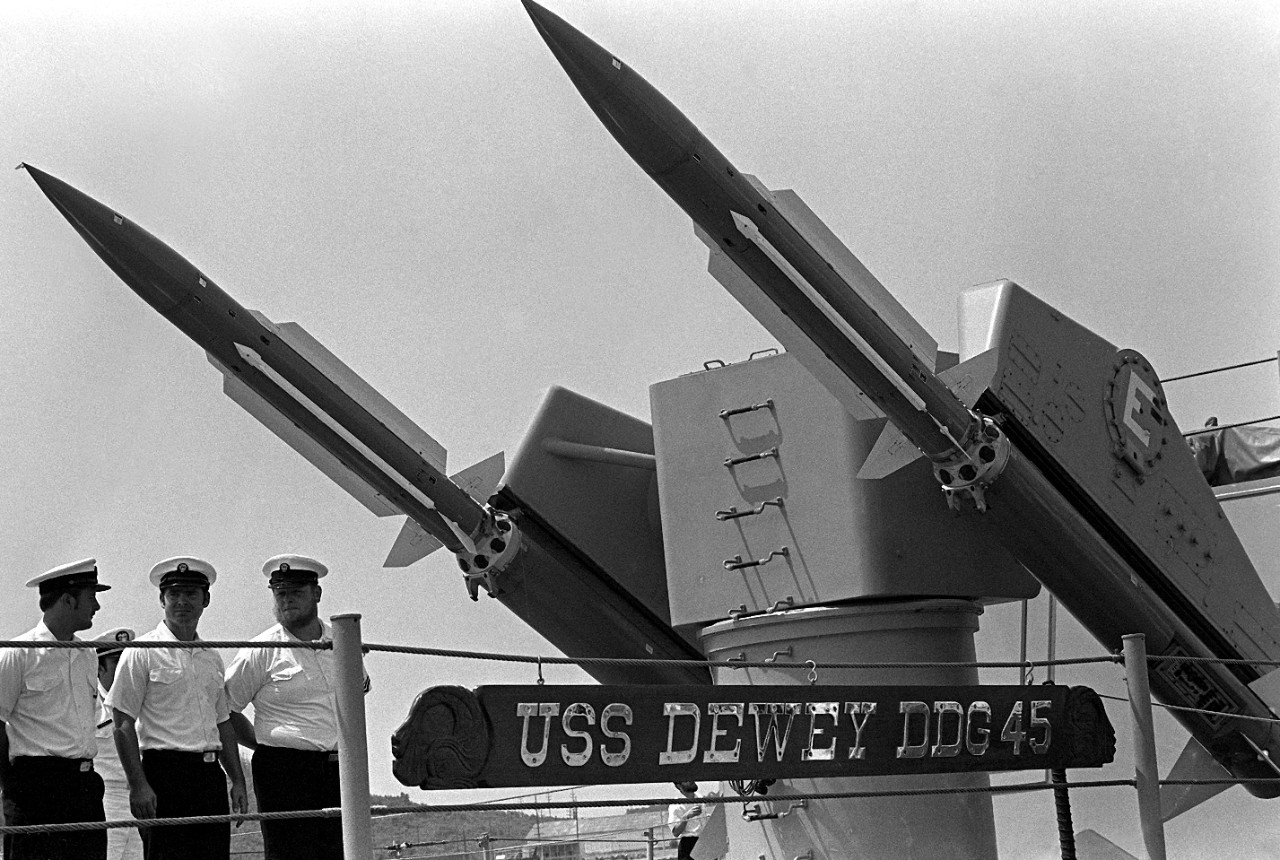 330-CFD-DN-SN-82-09474:  USS Dewey (DDG-45), 1979.   Crewmen stand at parade rest under the Mark 10 missile launcher aboard the guided missile destroyer as the ship gets underway for participation in exercise Unitas XX, June 1, 1979.  Photographed by PH2 J. Vinson, at Naval Station, Roosevelt Roads, Puerto Rico.   Official U.S. Navy photograph, now in the collections of the National Archives