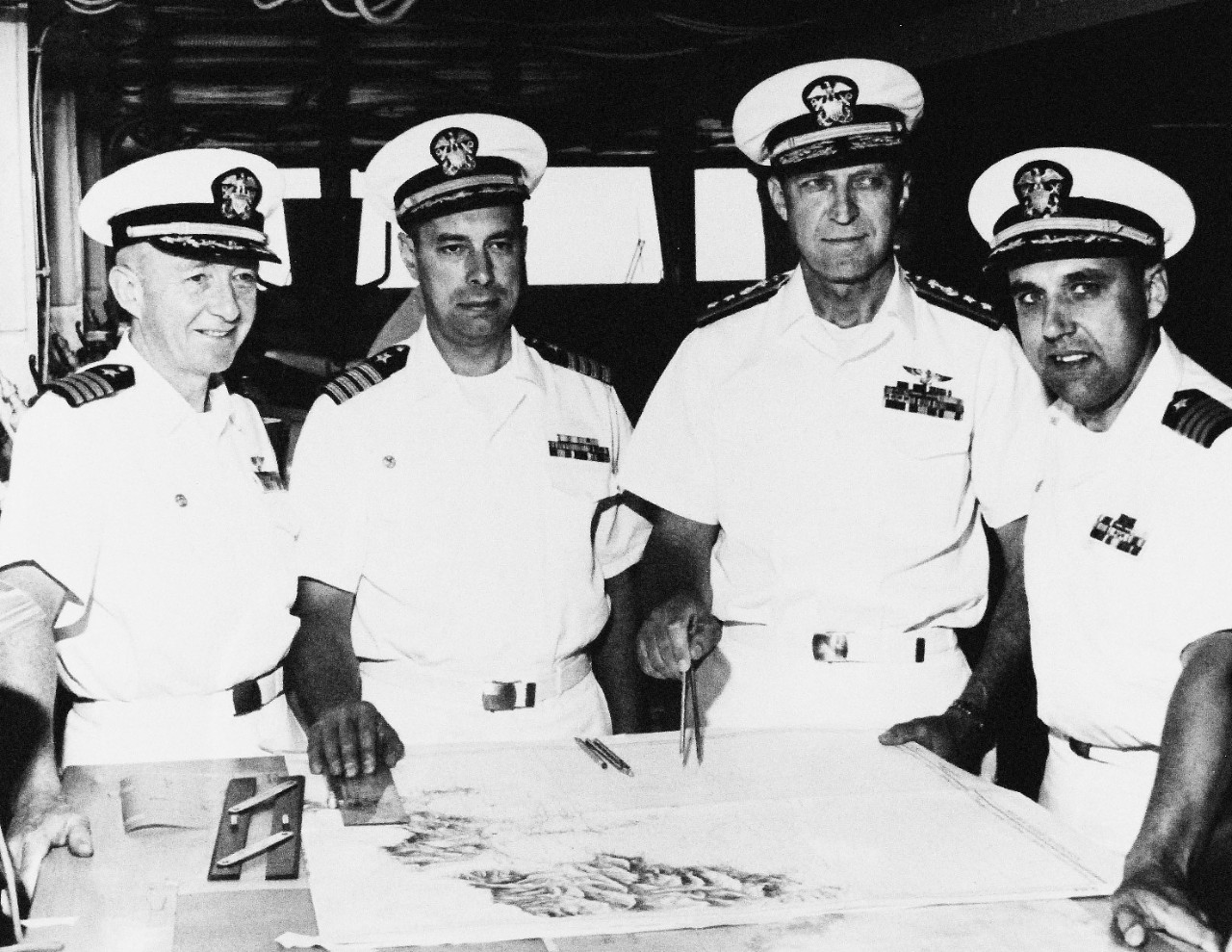 330-PSA-156-64 (USN 1103702):   Operation Sea Orbit, 1964.   A Ship Skippers Chart Course.  Commanding Officers of the nuclear powered USS Enterprise (CVN-65), USS Bainbridge (DLGN-25), USS Long Beach (CGN-9), confer with the commander of the world’s first Nuclear Task Group concerning the operations of the three ships.  Meeting on the bridge of the flagship Enterprise are, (left to right): Captain Frederick H. Michaelis (Enterprise); Captain Frank H. Price, Jr., (Long Beach); Rear Admiral Bernard M. Stream (Commander Nuclear Task Group 60.1) and Captain Raymond E. Peet (Bainbridge).   Photograph released July 24, 1964.  Official U.S. Navy Photograph, now in the collections of the National Archives.   (2015/11/03).