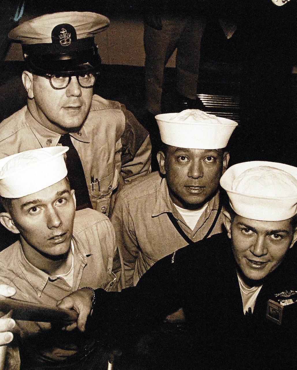 330-PSA-208-64 (USN 1105502):  Operation Sea Orbit, 1964.   The Navy men who had relatives aboard ships in the Great White Fleet, 1907-09, are, (left to right):  Aerographer’s Mate Third Class William C. Longstreet, USN, whose grandfather made the cruise in 1907; Chief Electrician’s Mate J.E. Norton, USN, whose uncle Joseph Starr was a Quartermaster with the Great White Fleet; Boatswain’s Mate Third Class Henry Lopez, who had an uncle, Eddie Romers, in the Great White Fleet, and Fireman William C. Stock, whose father sailed with the 16 battleships on their history making voyage.   Master caption:  Thee four sailors were aboard the nuclear powered aircraft carrier, USS Enterprise (CVAN-65), now nearing the end of 1 33,000 mile world cruise, have been following in the wake of relatives who circled the globe with the Great White Fleet more than 50 years ago.  Task Force One, composed of USS Enterprise (CVAN-65); USS Long Beach (CLGN-9), and USS Bainbridge (DLGN-25), left the Mediterranean July 31 and are scheduled to arrive in Norfolk, Virginia, October 3, after visitng ports in Africa, the Middle East, New Zealand, Australia, and South America.  Photograph released September 1964.  Official U.S. Navy Photograph, now in the collections of the National Archives.   (2015/11/03).