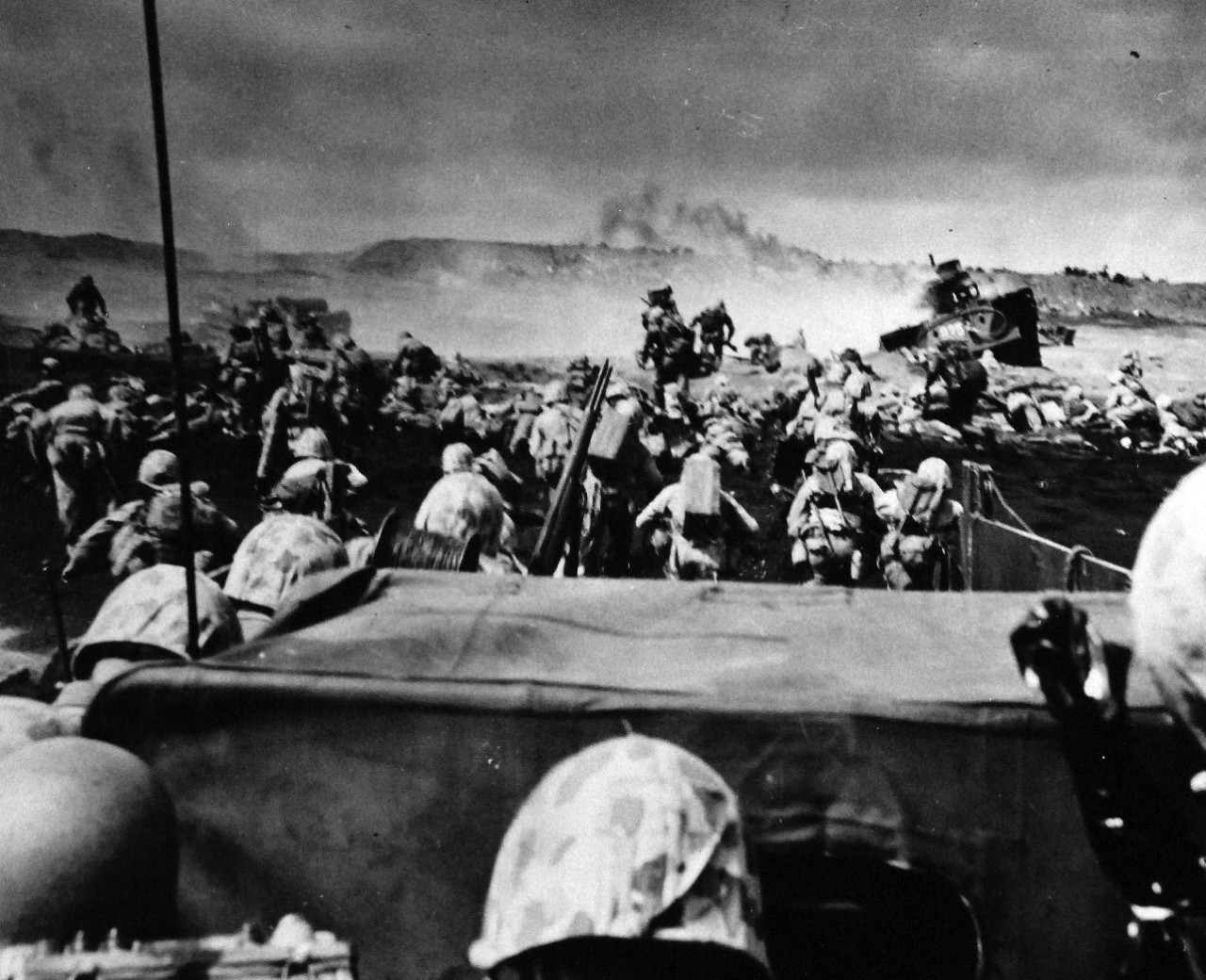 80-G-304843:  LCVP at Battle for Iwo Jima, February 19, 1945. A wave of Fourth Division Marines beginning an attack from the beach at Iwo Jima.  Another assault boat loaded with veterans is landed on the beach by an invasion craft.  Photograph released February 19, 1945.  U.S. Navy Photograph now in the collections of the National Archives.