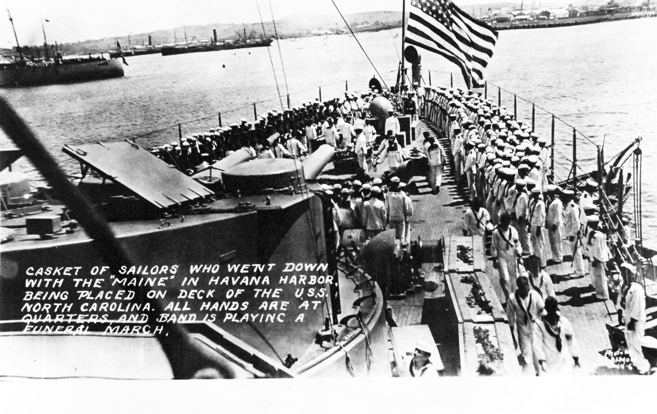 80-G-680183: USS Maine (1895-98), March 1912.  Casket of sailors who went down with the Maine in Havana Harbor being placed on deck of USS North Carolina (Armored Cruiser #12), March 1912.  All hands are at quarters and the band is playing a funeral march, received 14 September 1955.  Official U.S. Navy Photograph, now in the collections of the National Archives. (2014/04/03).    