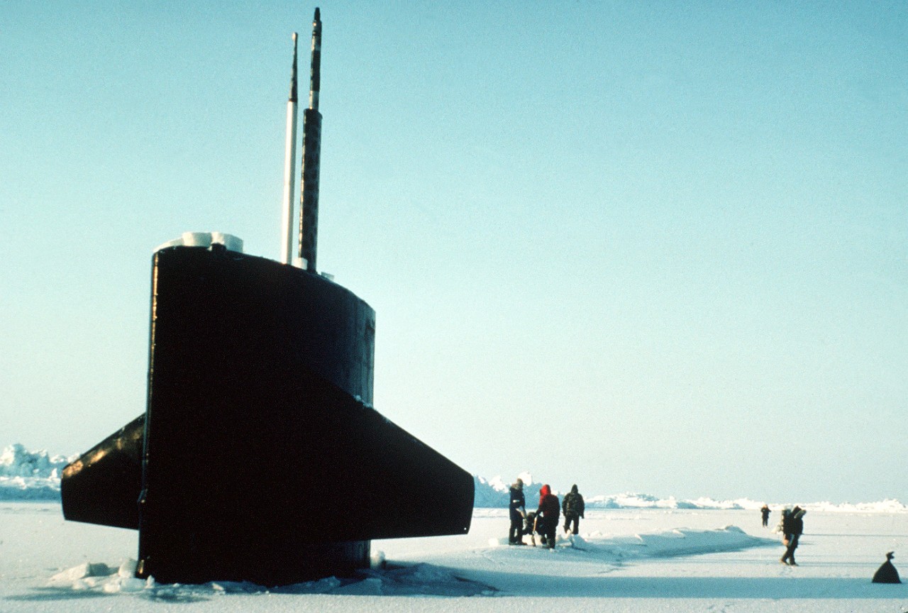 330-CFD-DN-ST-87-02290: USS Trepang (SSN-674), 1985.  The sail of the nuclear-powered submarine USS Trepang (SSN-674) protrudes from the ice near Ice Camp Opal, one of three research stations established on the polar ice cap during the Arctic Research and Environmental Acoustic (AREA) program. Area '85 is a Navy-sponsored expedition to study oceanography, acoustics, geophysics, communications and submarine warfare in the polar environment. Crew members are removing ice from one of the ship's hatches, July 5,1985. Photographed by JOC Fred J. Klinkenberger, USN.    Official U.S. Navy Photograph, now in the collections of the National Archives.   