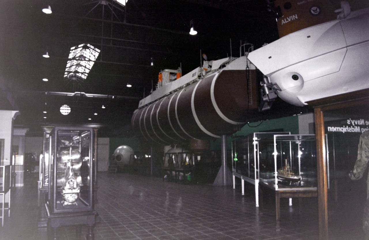 NMUSN-1029 (Color):    Bathyscaph Trieste, late 1990s.   View of bathyscaph on display.  Note the exhibit work space wall hasn’t been constructed yet.   National Museum of the U.S. Navy Photograph Collection.  