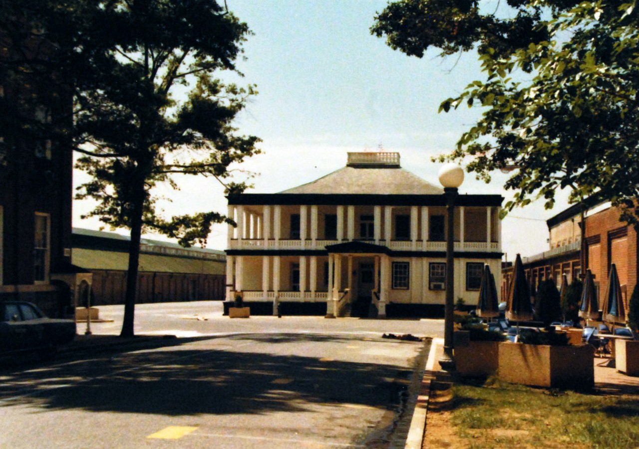 428-GX-KN-28810:  Building 1, Washington Navy Yard, 1979.   The Navy Yard Visitor Center, built in approximately 1838 as the Commandant’s Office, the building was used at one time as the first telephone exchange and, after 1947, as the Post Office. In later years, the building was converted to officer’s quarters.  It now serves the role again as the Commandant’s Office.   Photographed by PH3 Richard McDill, August 1979.  U.S. Navy Photograph, now in the collections of the National Archives.  