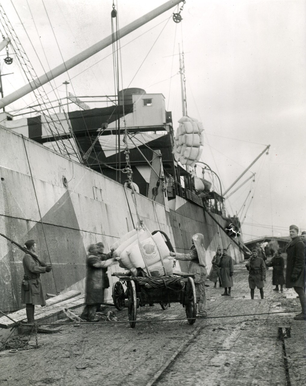 <p>111-SC-34629: Russian Intervention, 1918-20. Unloading grain from U.S. Cargo Ship Ascutney, at Archangel, 15 October 1918. Note, U.S. Army guards on pier. U.S. Army photograph, now in the collections of the U.S. National Archives. Copy of print located at NHHC.</p>
