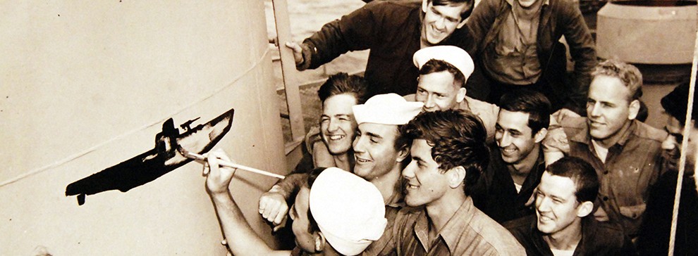 26-G-4451:    Sinking of German U-boat, U-853, May  1945.     Scratch another German U-Boat.   Jubilant over blasting a German submarine to the bottom in a recent sea fight, Coast Guardsmen aboard USS Moberly (PF-63) gather around the scoreboard to chalk up the victory.  Image pertains to U-boat, U-853.       Official U.S. Coast Guard Photograph, now in the collections of the National Archives.  (2017/09/05).