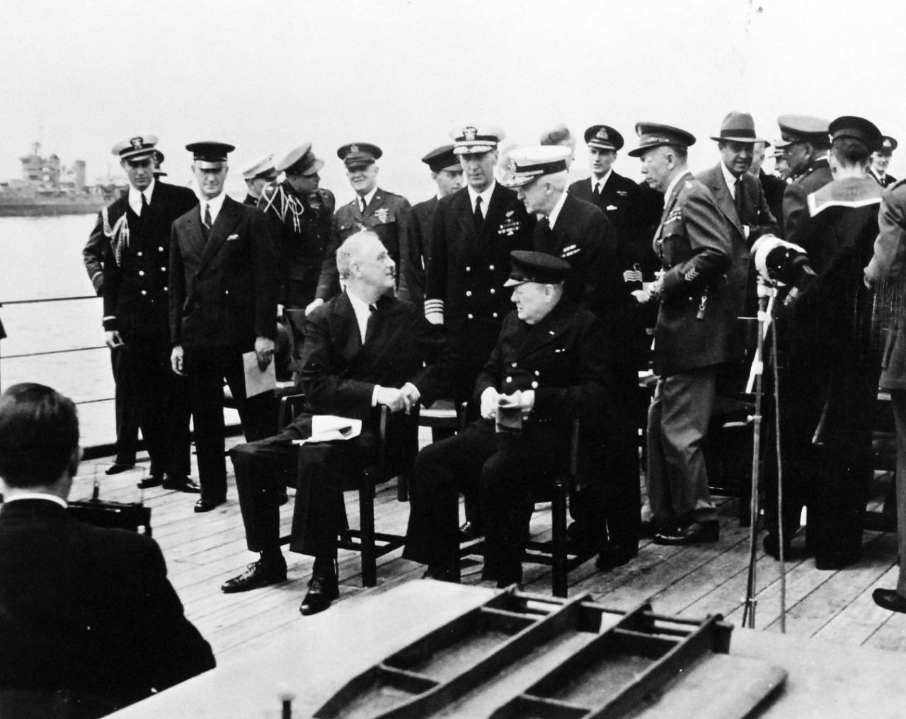 80-G-26864: Atlantic Charter, August 1941.  Informal group photograph including President Franklin D. Roosevelt and Prime Minister Winston S. Churchill on deck of HMS Prince of Wales following church services during the Atlantic Charter.  President Roosevelt is shown talking to Admiral Ernest J. King and Admiral Harold R. Stark.  Photograph released August 1941.   Official U.S. Navy Photograph, now in the collections of the National Archives.  (2016/03/22).