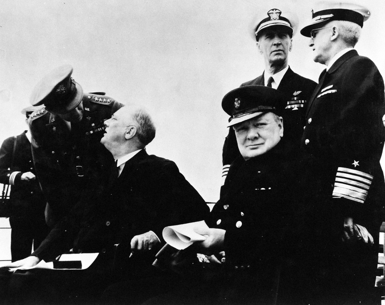 80-G-26881: Atlantic Charter, August 1941.  Informal group photograph including President Franklin D. Roosevelt and Prime Minister Winston S. Churchill on deck of HMS Prince of Wales during church services during the Atlantic Charter.  President Roosevelt chats with General George C. Marshall and Prime Minister Winston Churchill as they sit together.  Behind Churchill are:  Admiral Ernest J. King, (left) and Admiral Harold R. Stark, (right).  Photograph released August 1941.   Official U.S. Navy Photograph, now in the collections of the National Archives.  (2016/03/22).