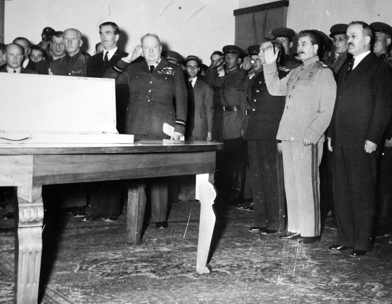 Lot 11597-4:  Tehran Conference, November-December 1943.   The presentation of the Stalingrad sword in the reception room of the Russian embassy.  Prime Minister Winston Churchill and Marshal Josef Stalin, hand upraised, during the playing of the Russian national anthem.  Anthony Eden is behind the Prime Minister; Stalin is flanked by General Voroshilov (right) and Foreign Minister Molotov, (left).  The sword was presented to the people of Stalingrad as a token of the regard and admiration of the British people for the gallant defense of the city. Note, V. M. Molotov, Peoples’ Commissar for Foreign Affairs, to Stalin’s right.  U.S. Army photograph from the collection of the Office of War Information.  Courtesy of the Library of Congress.    (2016/01/15).