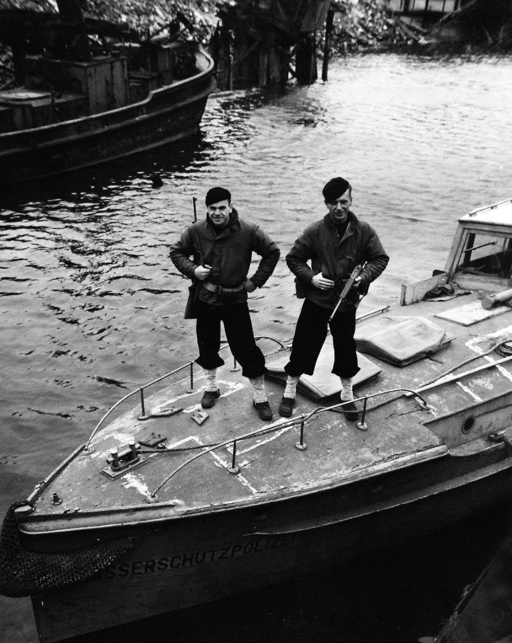 80-G-49282:   U.S. Navy in Germany, 1945.   Left to right:  SP(S)1/C J.E. Simmons and SP(S)2/C Edmond Norton stand guard over a former Nazi police boat in the harbor area of Bremen, Germany.   Photograph released May 29, 1945.  Official U.S. Navy photograph, now in the collections of the U.S. Navy.   (2014/12/02).   