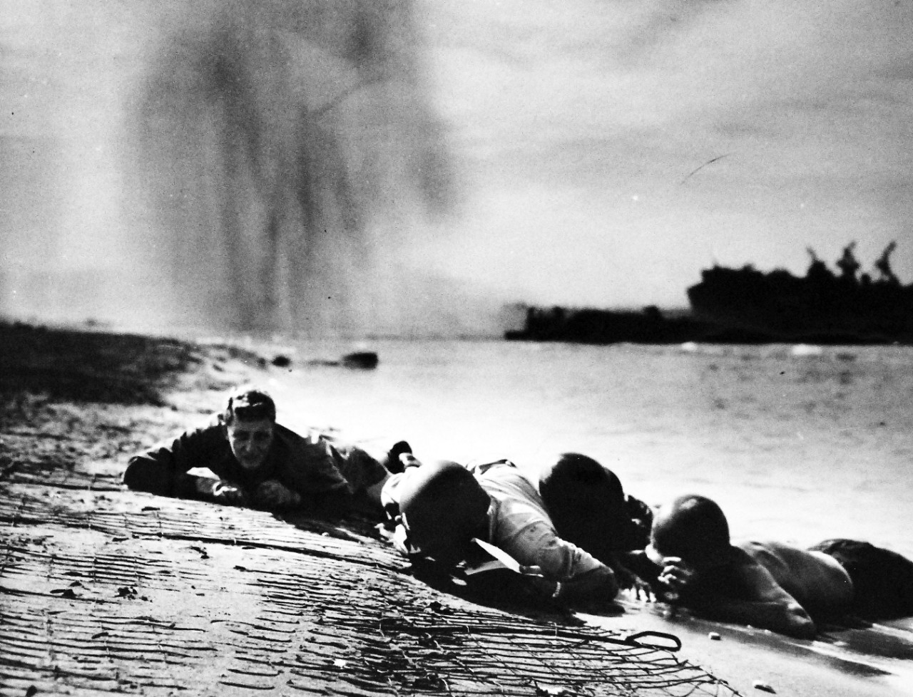 26-G-2000:   Operation Avalanche, September 1943.  Underneath Dropping Bombs.  U.S. Coast Guardsmen and Navy beach battalion men are shown hugging the shaking beach at Paestum, just south of Salerno, as a German bomber unloads on them.  In the background of the picture, one of the most outstanding of the war, debris from a bomb hit can be seen in the air.  Coast Guardsmen said this was much worse than the Sicilian and North African invasions, in which the Coast Guard also participated.   Official Coast Guard Photograph. Photographed through Mylar sleeve.   Courtesy of the Library of Congress.  (2016/05/19).