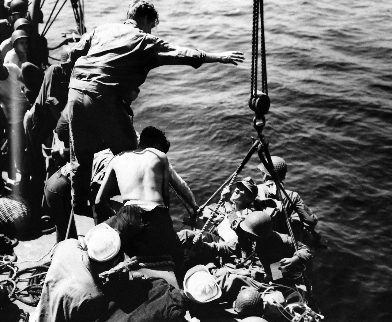 26-G-2002:   Operation Avalanche, September 1943.  Coast Guardsmen Help Wounded Aboard.  U.S. Coast Guardsmen help slightly wounded soldiers, including the German wearing a peaked cloth cap, come aboard the combat transport lying off Paestum, just south of Salerno and one of the invasion points.  Coast Guardsmen manned combat transports and landing craft.    Official Coast Guard Photograph. Photographed through Mylar sleeve.   Courtesy of the Library of Congress: Lot-916.  (2016/05/19).