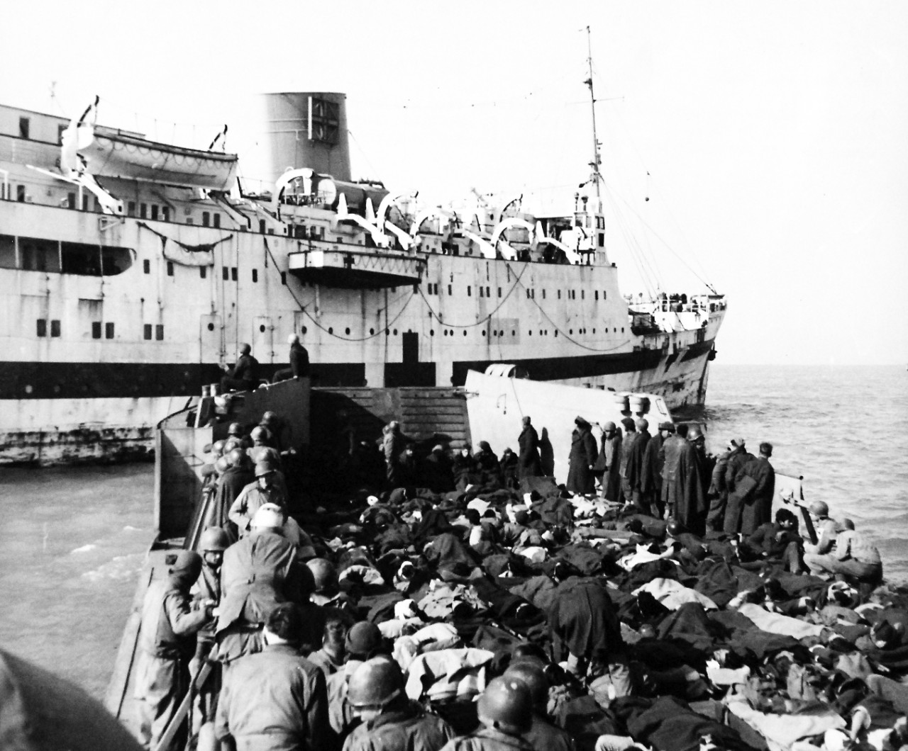 80-G-58426:  Battle of Anzio, January-June 1944.    Americans and English casualties ride out to the hospital ship RMS Leinster in the Anzio harbor aboard an LCT.  Hospital corpsmen and Red Cross workers accompany them.     Photographed March 3,  1944.  Official U.S. Navy photograph, now in the collections of the National Archives.  (2016/06/28).
