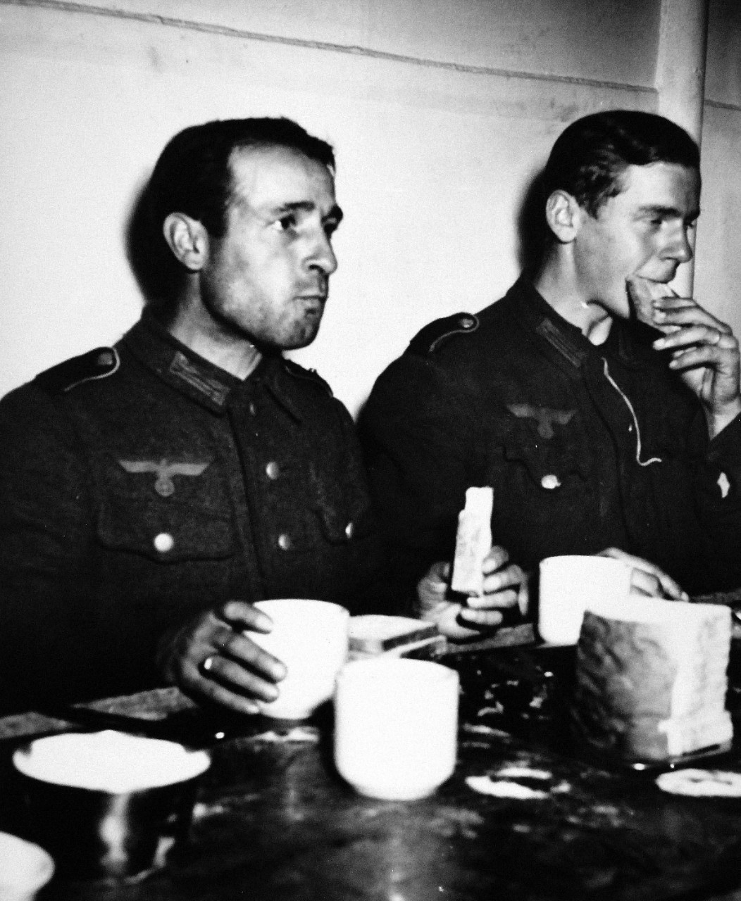 26-G-2432:  Normandy Invasion, German Prisoners, June 1944.  The Awakening.  On Board a U.S. Coast manned troop transport headed for the United States, two Nazi prisoners present a picture of downcast disillusion as they hungrily munch the first white bread they have tasted in many months.  Captured in the irresistible Yankee push from the Normandy beaches toward Cherbourg, these ex-supermen have been rudely awakened from mad Hitlerite dreams of world conquest.  The first shipment of hundreds of Nazis captured in France has just arrived at an Atlantic port, June 1944. U.S. Coast Guard Photograph, now in the collections of the National Archives.  (11/18/2014).  