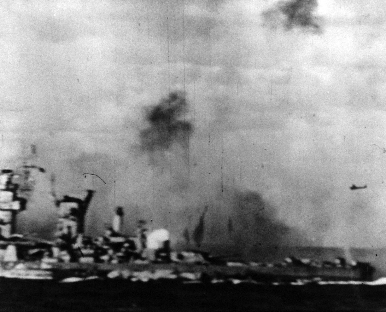 80-G-49696: Japanese Kamikaze Attack, June 1945. Japanese suicide planes streak near a Navy battleship with anti-aircraft batteries blazing at the enemy plane.   Released June 28, 1945.   Official U.S. Navy photograph, now in the collections of the National Archives.  