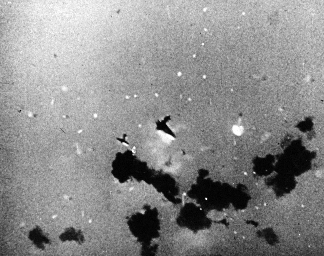 80-G-49873: Japanese Kamikaze Attack, July 1945. Stills from the U.S. Navy, Marines and Coast Guard film, “The Fleet That Come To Stay.”  Shown:  Disintegrating in mid-air after being hit by USN anti-aircraft fire.  A Japanese Kamikaze flutters to the sea.   Received July 18, 1945.   Official U.S. Navy photograph, now in the collections of the National Archives.  