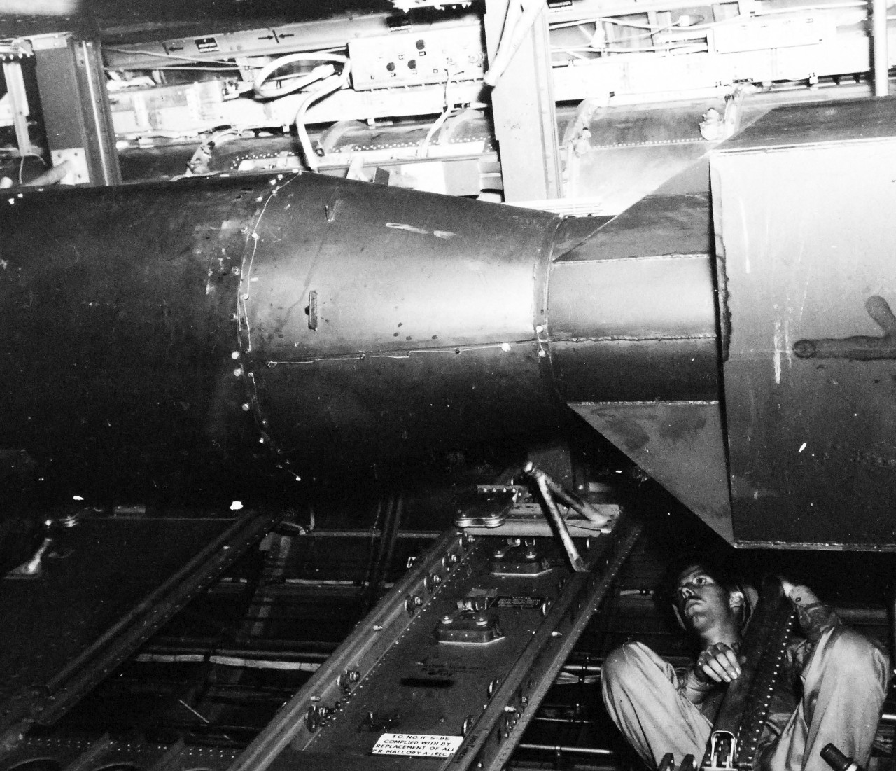 77-BT-132:    Tinian Island, August 1945.   Atomic bomb, Little Boy, in bomb bay of B-29 Superfortress, Enola Gay.  S. Dike is examining fit of unit.   Official photograph of the Office of Chief of Engineers, now in the collection of the National Achives.   (2015/08/25). 