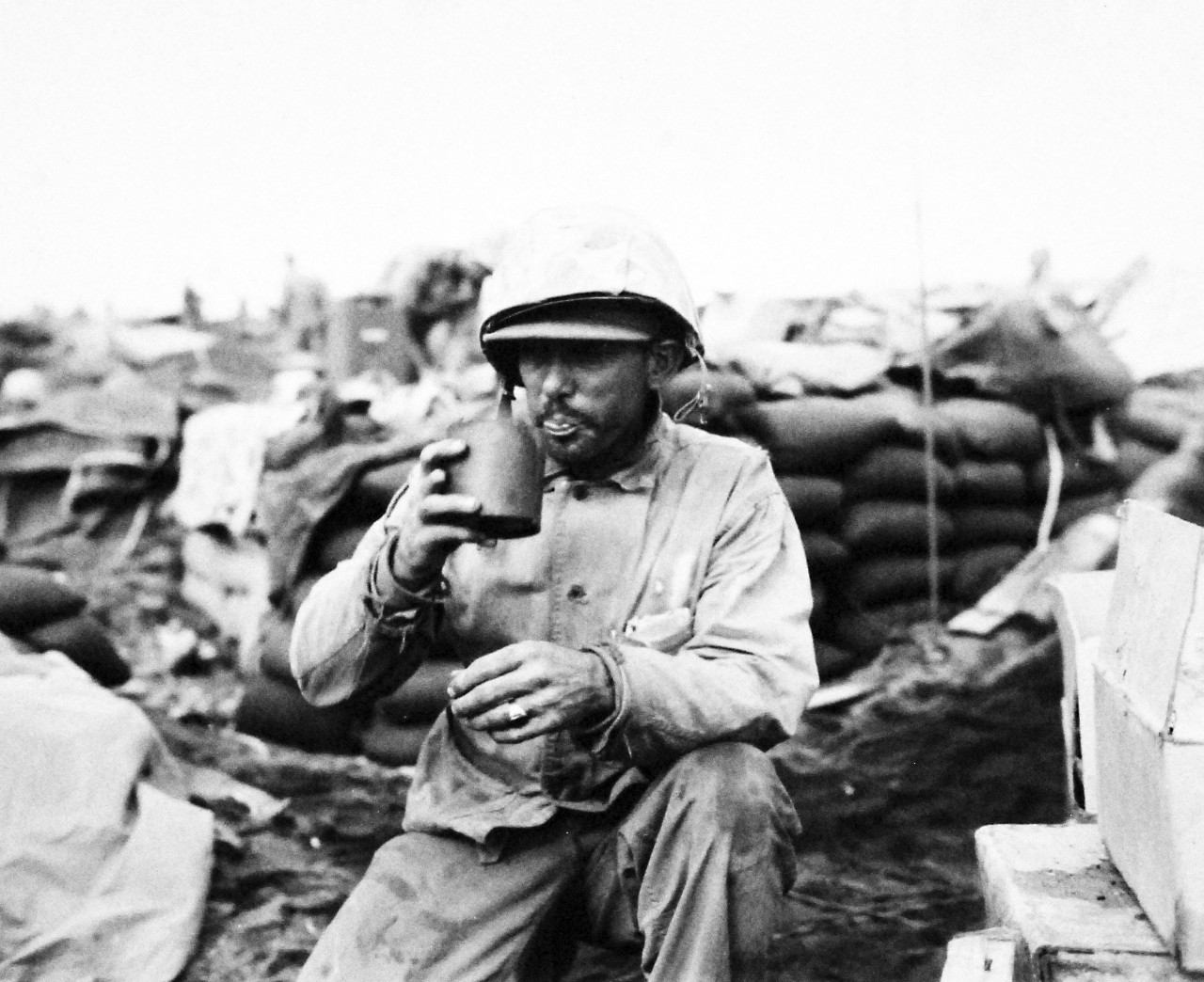 127-GW-321-109806: Iwo Jima Operations, February-March 1945.   Sergeant Alfred Metivier, USMC, sits on the beach at Iwo Jima after a grueling night at his 75 art.  Piece drinking a “cup” of coffee. The container used is a cop from a 75mm shell case.   Photographed by L.W. Weber, February 1945.  Official U.S. Marine Corps Photograph, now in the collections of the National Archives.  (2016/09/06).