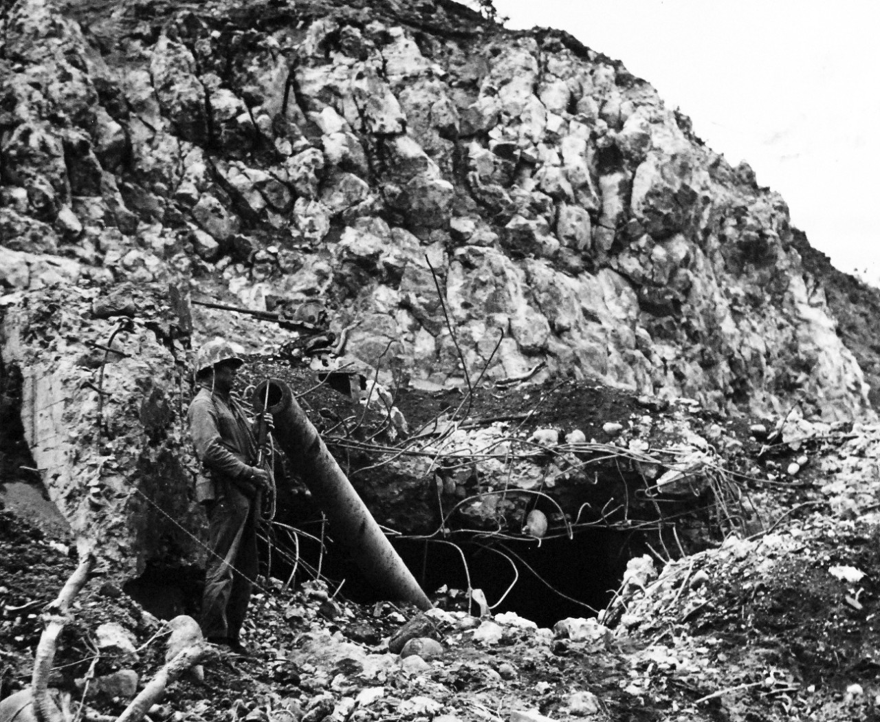 80-G-304846:  Battle for Iwo Jima, February-March 1945. A wave of Fourth Division Marines beginning an attack from the beach at Iwo Jima.  The rugged cliff above made this mighty Japanese emplacement at the foot of Mount Suribachi almost completely impregnable.  This photograph of the wrecked gun was taken on the fifth day of the Iwo Jima struggle.   Photograph released February 24, 1945.  Official U.S. Navy Photograph now in the collections of the National Archives.  (2016/01/19).