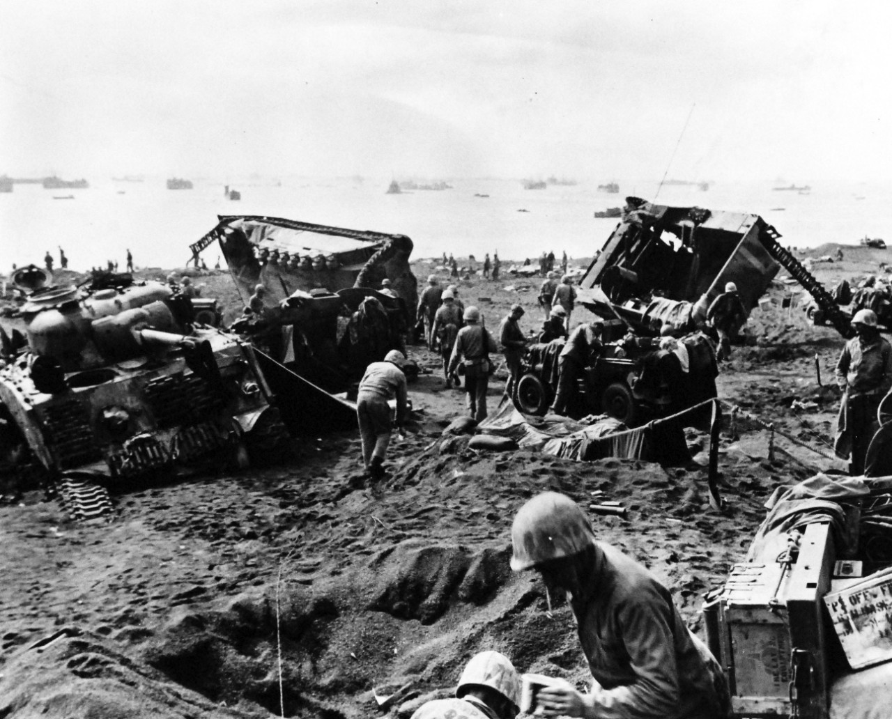 80-G-304850:  Battle for Iwo Jima, February 19, 1945.  Stalled and wrecked vehicles of Marines bagged down in soft Volcanic ash on beach of Iwo Jima were targets for Japanese mortermen who fired down from mountain overlooking beach D-Day.  Amtracs and medium tanks of Blue Beach #1.  Some of the 800 ships that took part in the action are in the background.  Photographed February 19, 1945.  U.S. Navy Photograph now in the collections of the National Archives.  (2016/01/19).