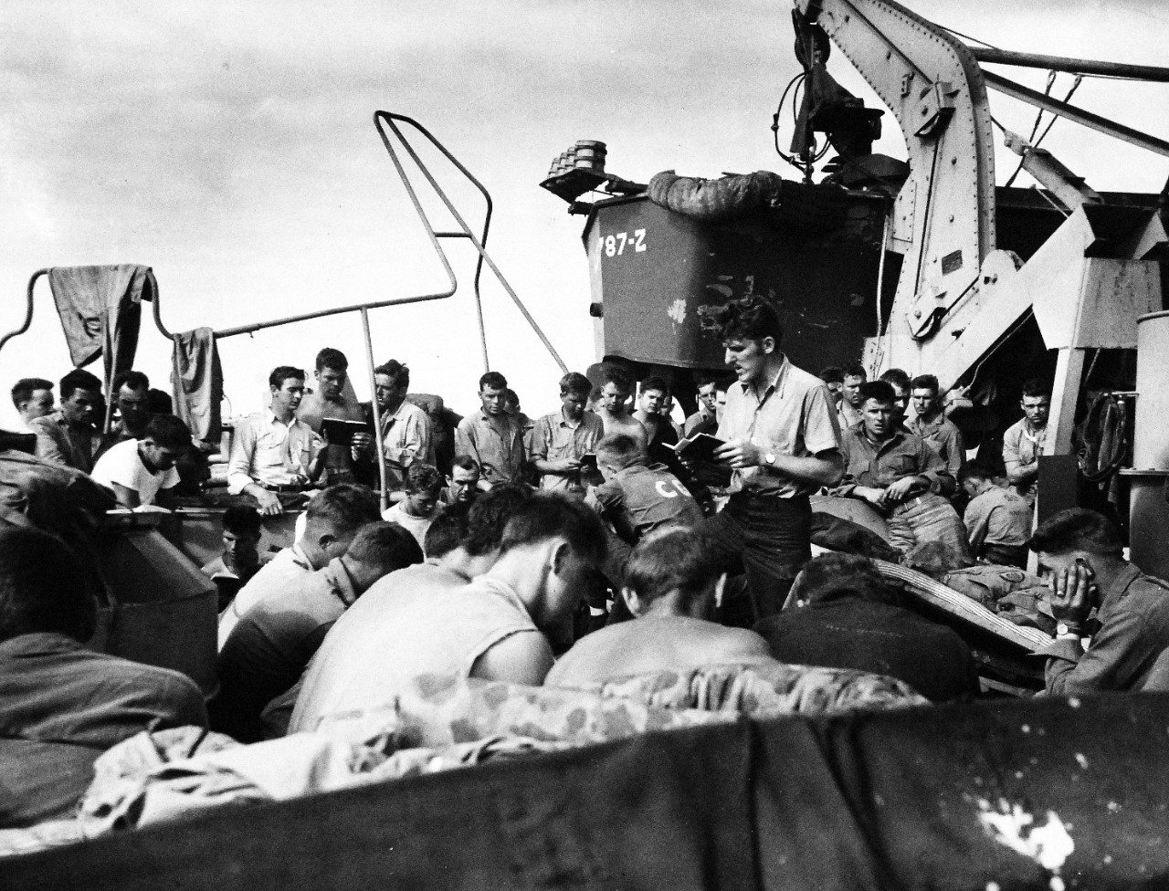 80-G-304870:  Battle for Iwo Jima, February 19, 1945. PHoM2/C Charles R. Roth, USCG, leads hymn singing and gives brief talk to his shipmates aboard a Coast Guard-manner LST the day before landing on Iwo Jima.   Photographed February 18, 1945.  Official U.S. Navy Photograph now in the collections of the National Archives.  (2016/01/19).