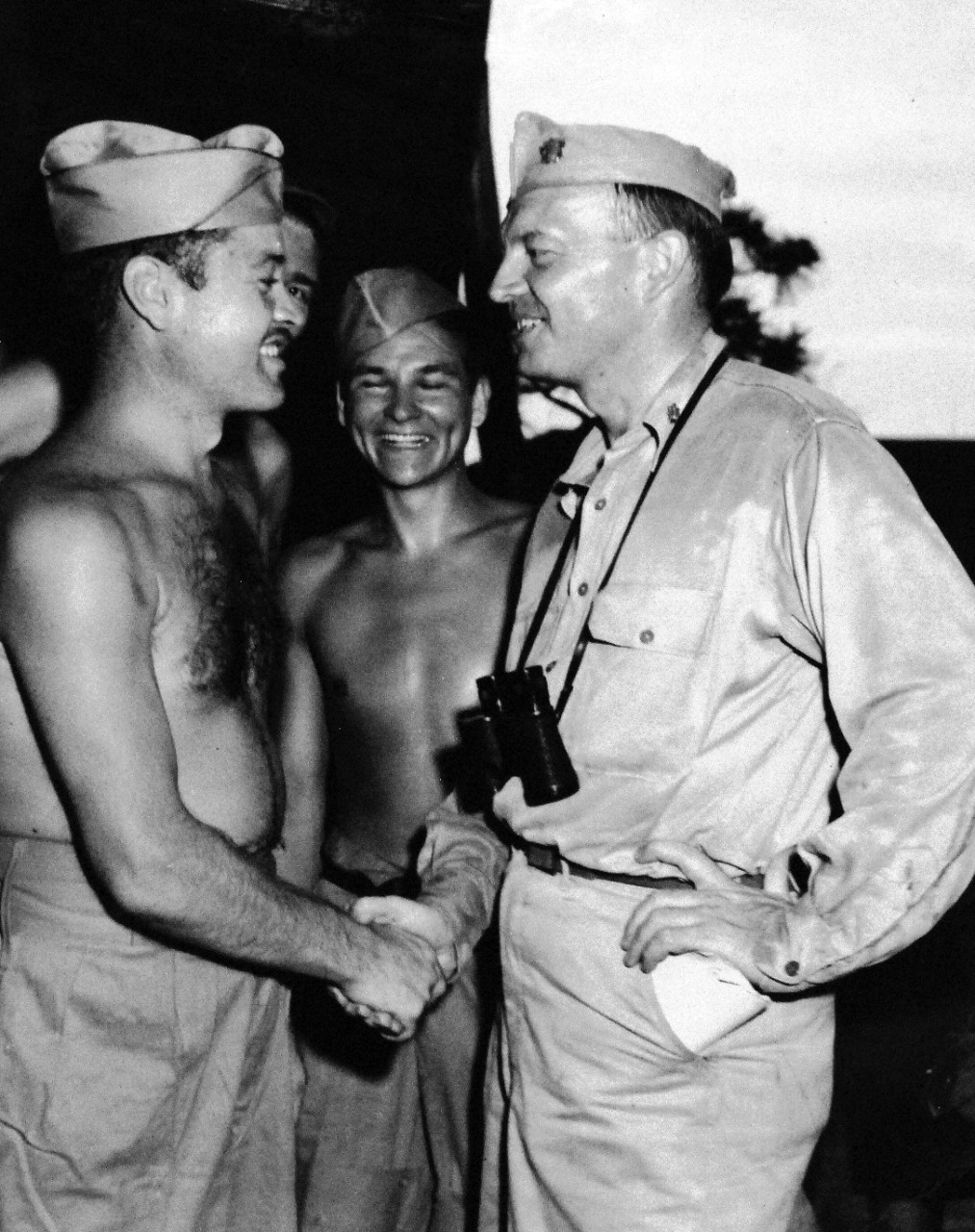 80-G-490443:   Major Gregory “Pappy” Boyington, USMC, 1945.    Boyington, a flying ace, who was reported missing for 16 months, as seen after his rescue from prison camp hospital at Omori near Tokyo.  Shown:  Commander Harold E. Stassen, right of the staff of Admiral William F. Halsey, USN, greets the Major.  Boyington later received the Medal of Honor for his actions during the war.   Photograph dated August 29, 1945.  Official U.S. Navy photograph, now in the collection of the National Archives.   (2015/11/10).