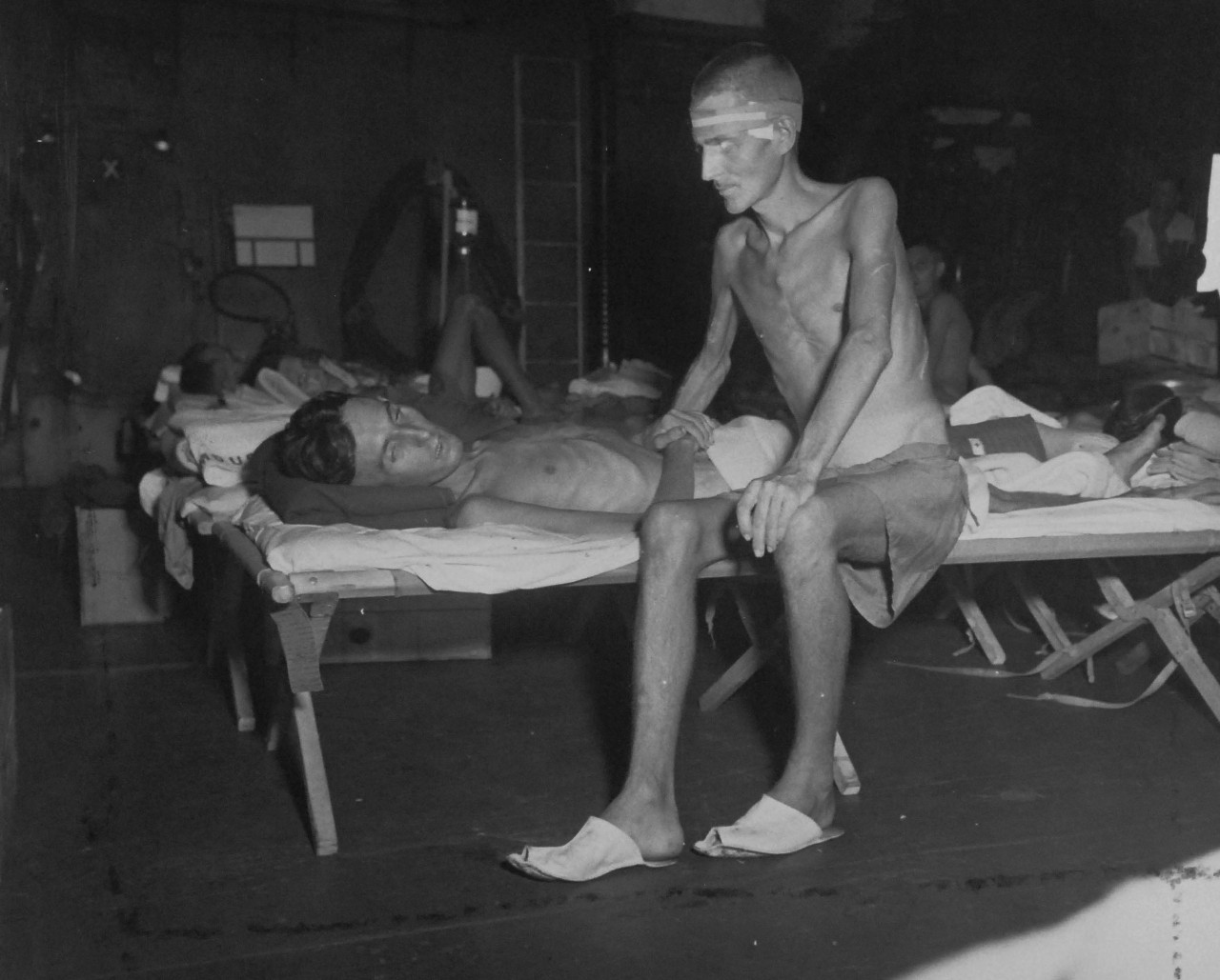 80-G-490492-A:   Allied Prisoners of War, Formosa, 1945.   CP1 Gordon James Clark and Gunner R.A. Norman Hill, from England, are walking skeletons as they relaxed at last on the hangar deck of USS Block Island (CVE 106), which liberated them from Formosa.  These men were captured at Singapore.   Photograph released September 5, 1945.  Official U.S. Navy photograph, now in the collections of the National Archives.  (2014/05/29).    The original is a small photograph.   