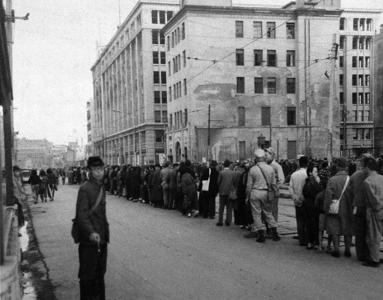 80-G-264851:   Occupation of Japan, 1945.    Scene at Sasebo, Kyushu, Japan, shows people lined up for trolley car on Ginza Street.  Photographed by crewmember of USS Chenango (CVE-28), released October 19, 1945.   Official U.S. Navy photograph, now in the collection of the National Archives.  (2015/12/01).