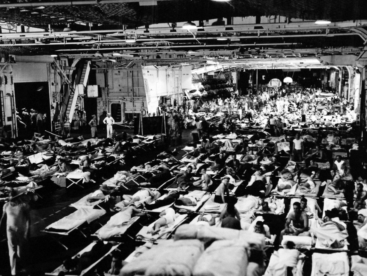 80-G-495657:   Operation Magic Carpet, 1945.   Returning veterans of the Pacific fill the hangar deck of USS Enterprise (CV 6) as it stopped in Pearl Harbor preparatory to moving to the United States.  This is how the carrier looks at night when some of the 1,200 enlisted passengers prepare for bed, September 1945.  Official U.S. Navy photograph, now in the collections of the National Archives.   (2014/5/29). 