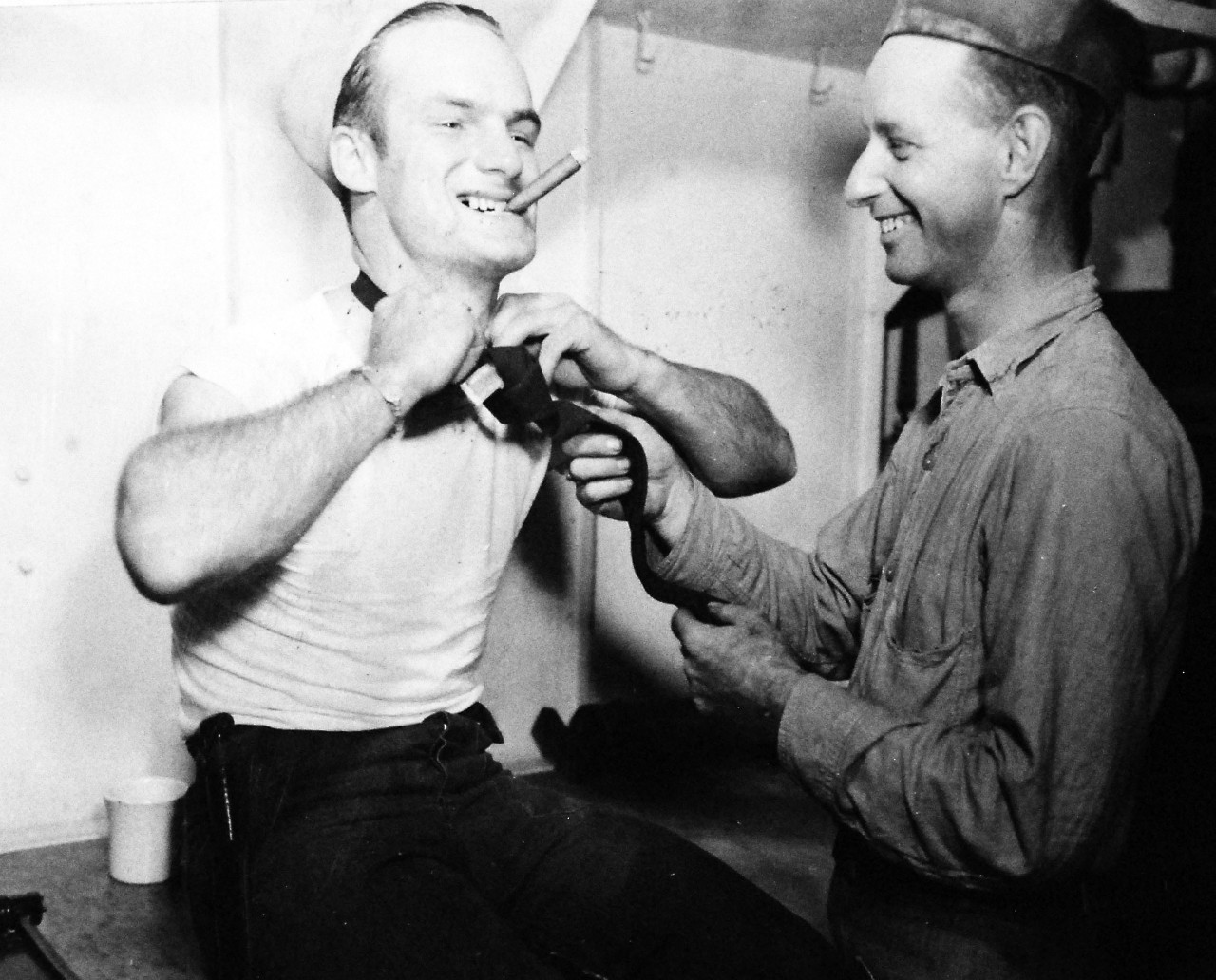 80-G-354681:  V-J Day, August 15,1945.    Aboard USS Ticonderoga (CV-14), PhoM3/C Duane L. Corkrum and PhoM3/C Marshall F. Hosp, practice tying a civilian tie after the announcement of V-J Day.   Photographed by PhoM3/c J.D. McGhie.    Photographed August 15, 1945.  Official U.S. Navy photograph, now in the collections of the National Archives.  (2016/06/21).