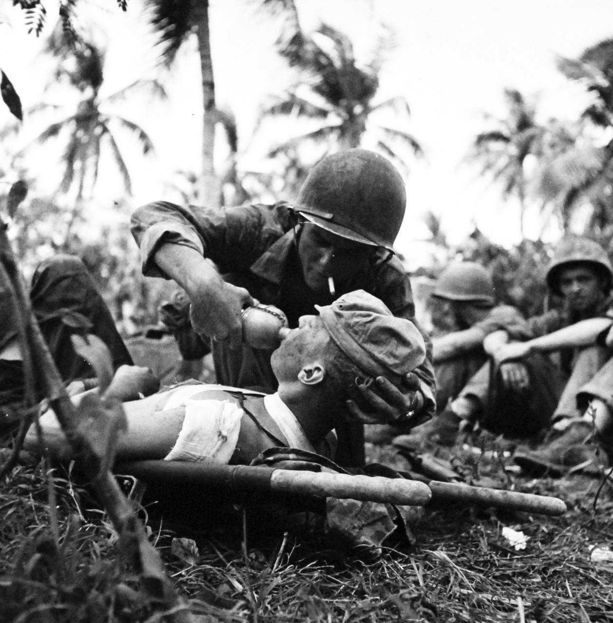 80-G-475151: Invasion of Guam, July 21-August 10, 1944 .  U.S. Navy Corpsman gives drink to wounded U.S. Marine on Guam.  Photographed by Lieutenant Paul Dorsey, July 1944, TR-10753.      Official U.S. Navy photograph, now in the collections of the National Archives.   (2017/03/15).