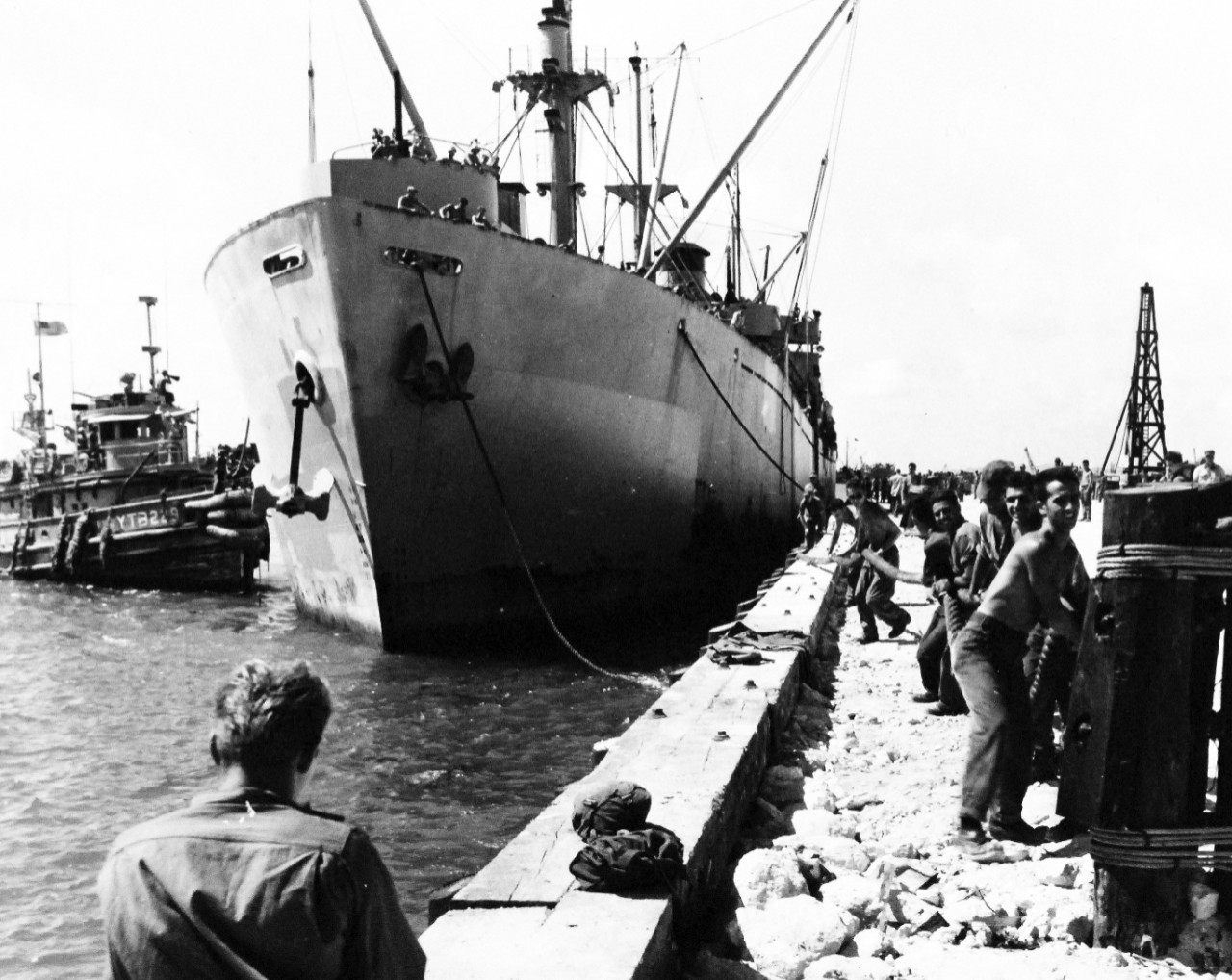 80-G-349316:   Okinawa Campaign, Landing, April 1945.    SS Sylvester Pattie, Liberty Ship, was the first large American vessel docked at Okinawa since the April 1st invasion.  It was docked at a new fire proof fuel pier which had just been completed by the 7th Seabees in Buckner Bay, off Katchin Hanto, Okinawa.  Shown:  Navy Seabees in the right foreground were about to secure a line to the three-pile mooring ballard immediately in front of them.  Aft, a similar line was secured to 19-pile dolphin (mooring post) just off the outer end of the pier.  In the background, across the pier from the ship, a pile driver may be seen.  It had finished its final work, for this pier, in driving the piles for the dolphin.  Note USS YTB 229. Photograph released October 22, 1945. Official U.S. Navy photograph, now in the collections of the National Archives.  (2015/12/22)