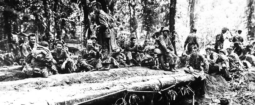 80-G-207836:  Marine position on front lines at Bougainville in the Solomon Islands.   Halting for a short rest.  In foreground is newly erected bridge over a gulley.  Photograph released January 14, 1944.    U.S. Navy photograph, now in the collections of the National Archives.  (2016/06/21).