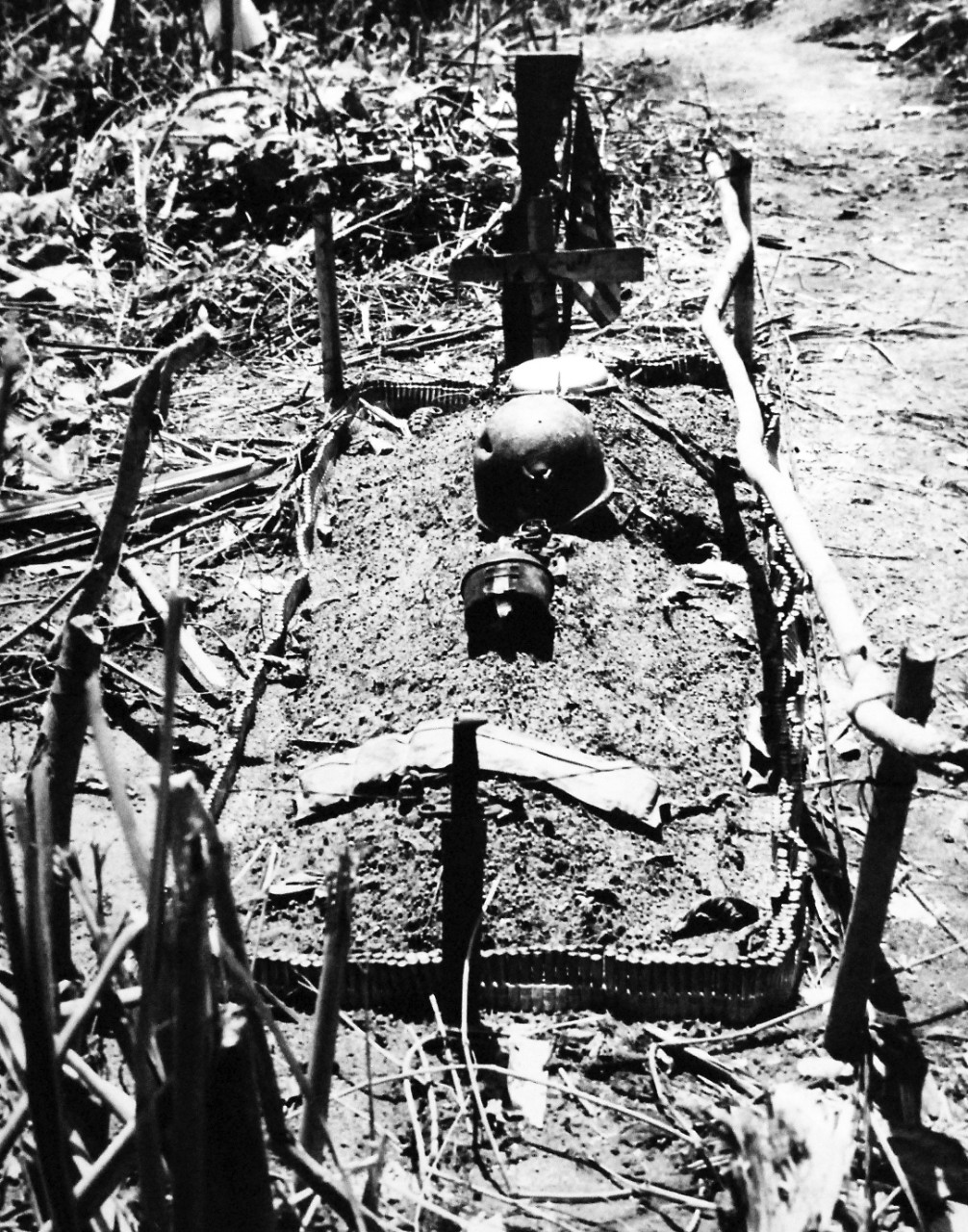 80-G-207839:  Bougainville Campaign, November 1943-August 1945.   Machine-gun bullets, outline grave of Marine paratrooper buried on the spot where he was killed on Hallzapoppin Ridge, Bougainville.  Near the crude cross marking, the grave is a flag and rifle.  A bullet-ridden helmet and mess gear are also on the grave.   Photograph released January 14, 1944.    U.S. Navy photograph, now in the collections of the National Archives.  (2016/06/21).